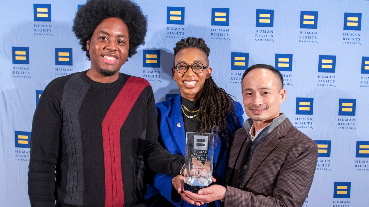 Axiom employees, Kyle Ireland and Loun Khammy, holding Human Rights Campaign (HRC) award with HRC President Kelley Robinson