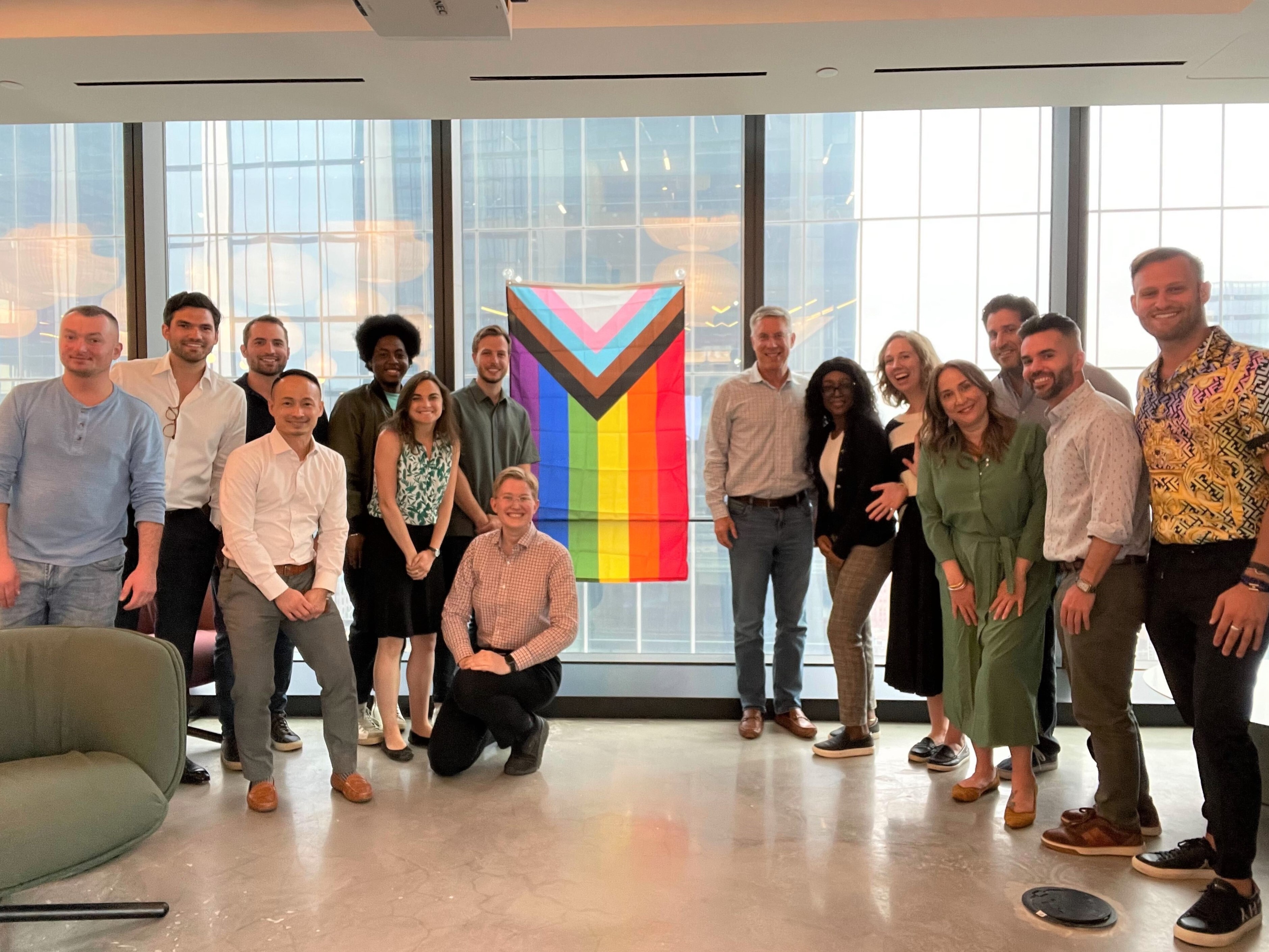 Axiom's CEO stands in front of Pride flag with group of Axiom employees